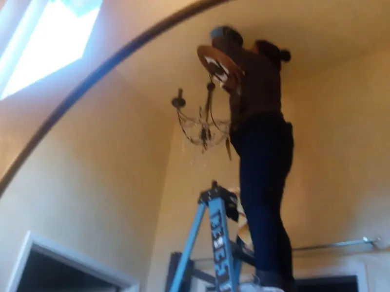 Electrician installing a chandelier in a Security-Widefield residence